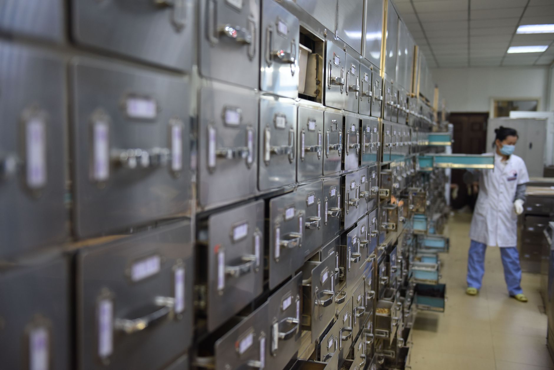rows of laboratory sample storage units in a pharmaceutical research facility, with automated robotic arms positioned along a sterile processing aisle