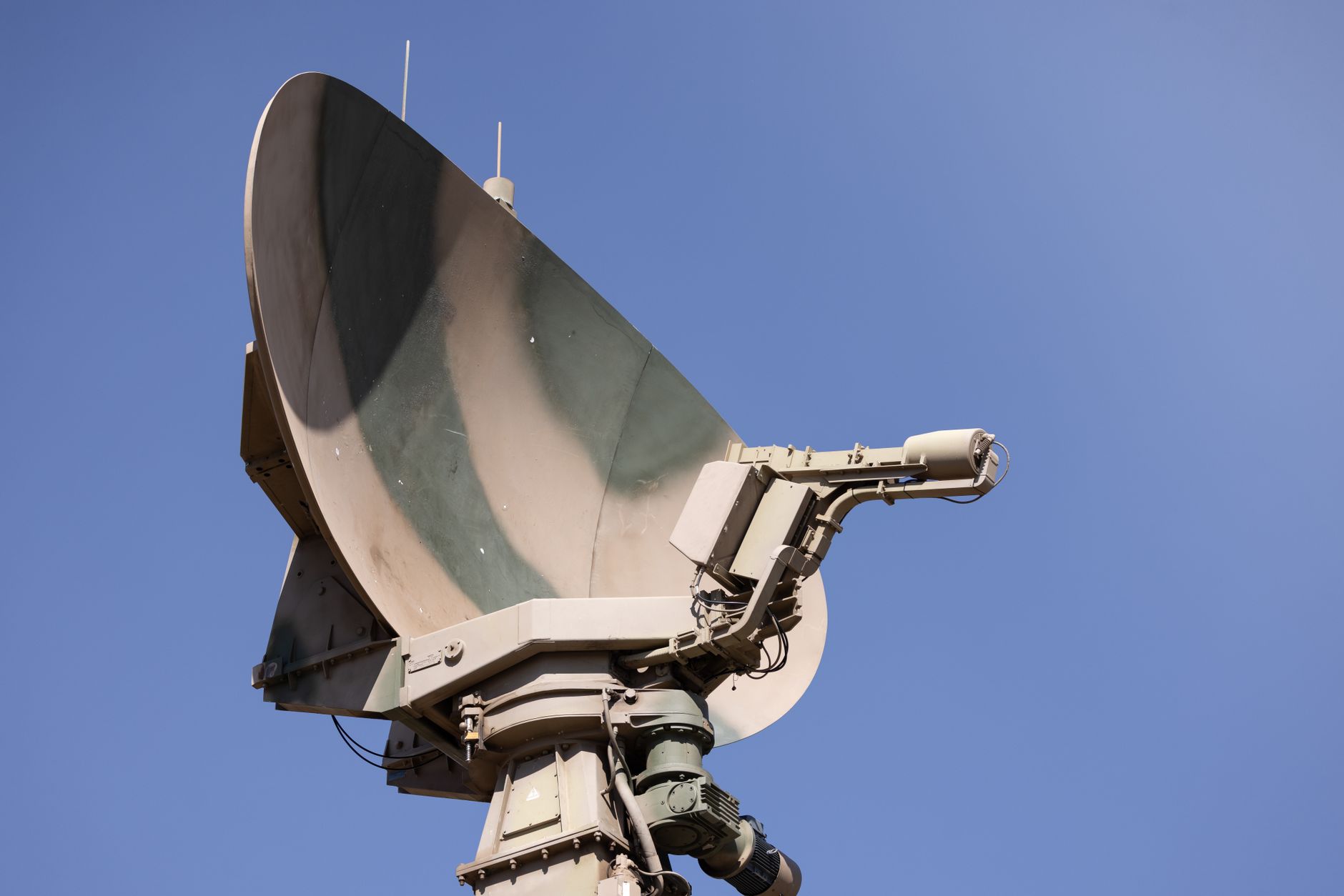 a ground satellite dish array pointed skyward at dusk, surrounded by low scrubland, with a clear sky transitioning from blue to orange above