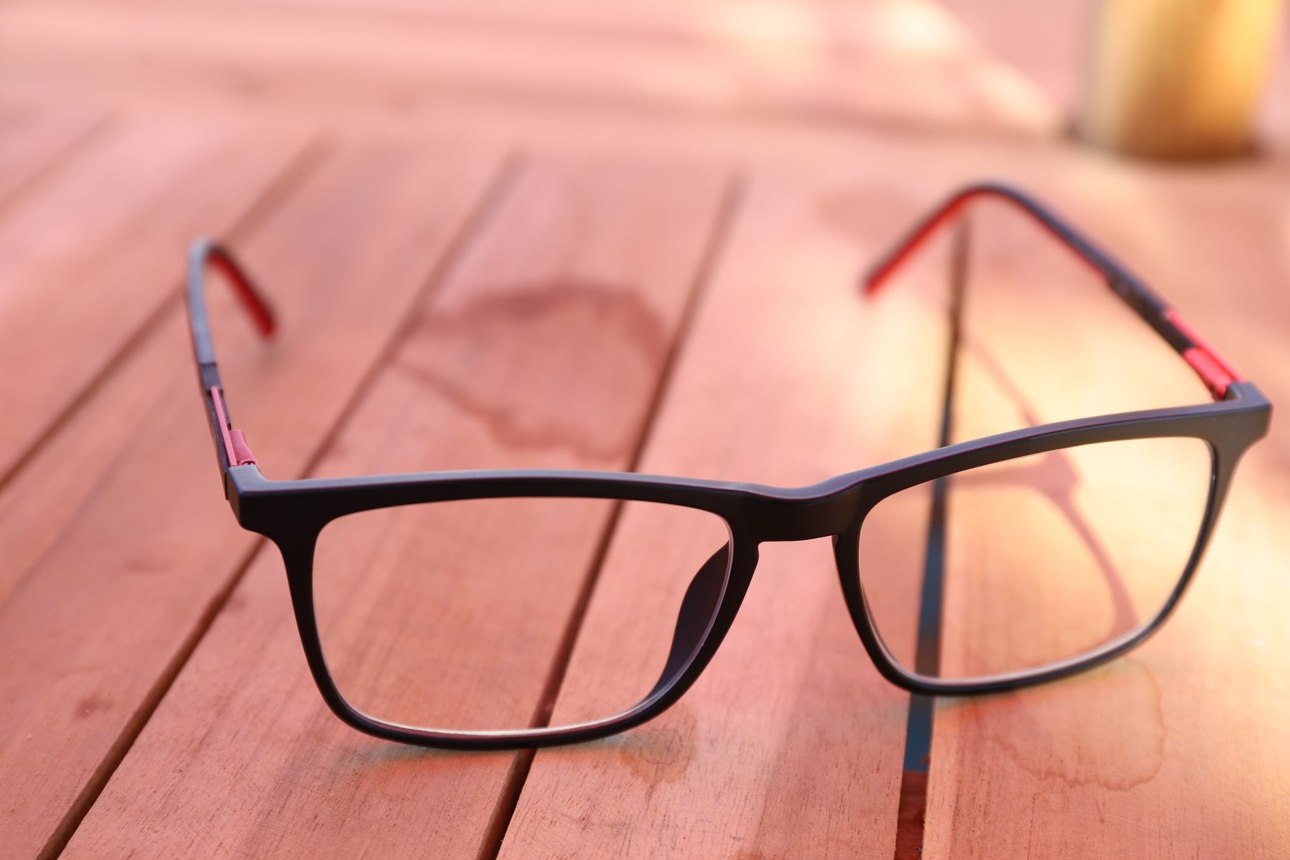 a pair of sleek, lens-equipped smart glasses resting on a wooden surface, showing the subtle waveguide display elements embedded in the lenses, natural light environment