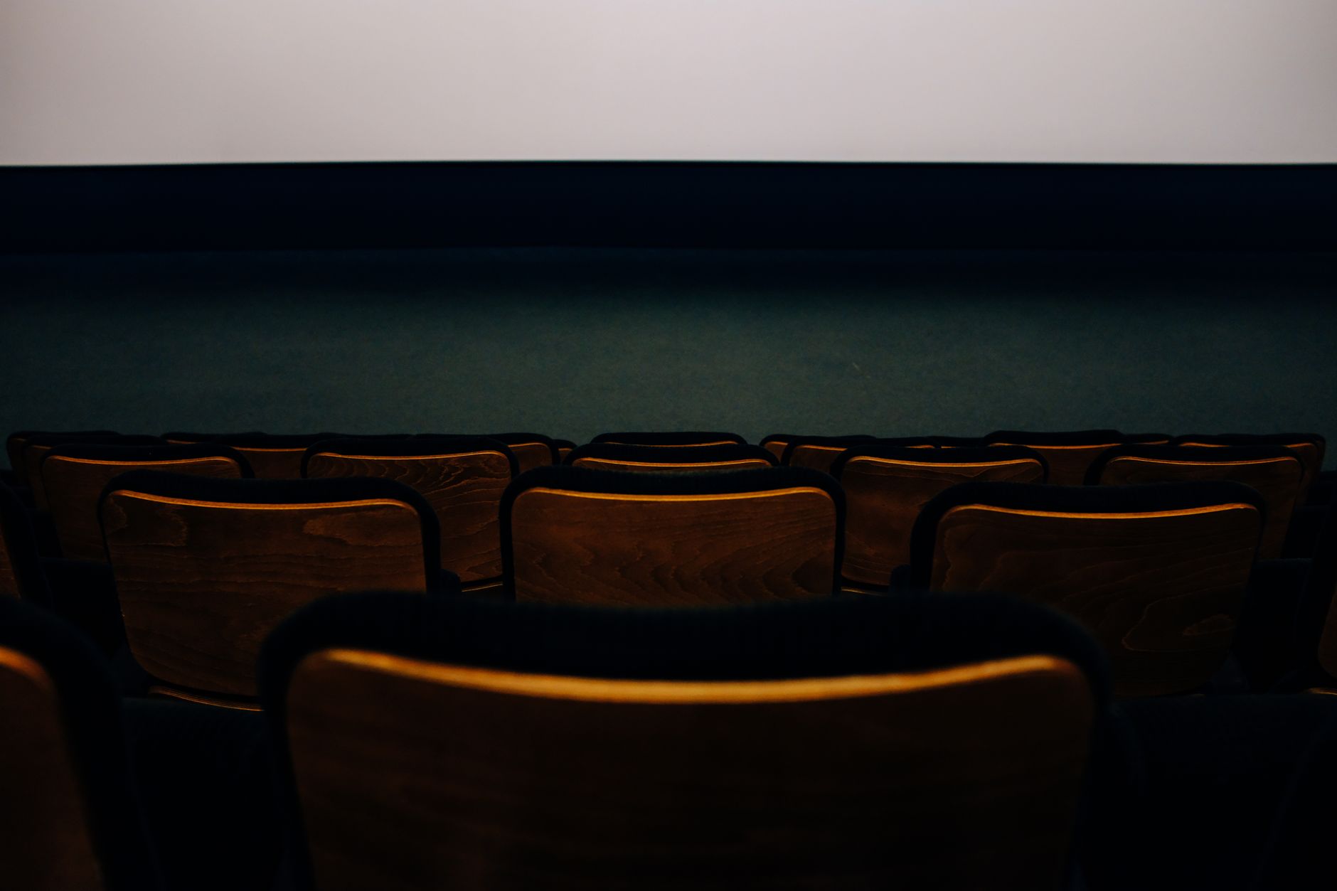 a large outdoor film premiere screen displaying a dystopian arena landscape, surrounded by an empty theater venue at dusk