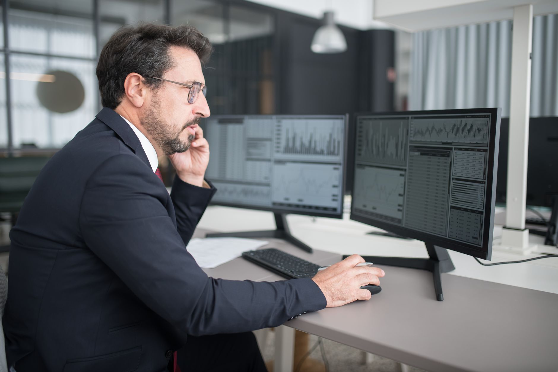 a dual-monitor trading desk setup showing financial news websites with native advertisement placements visible in the content feed