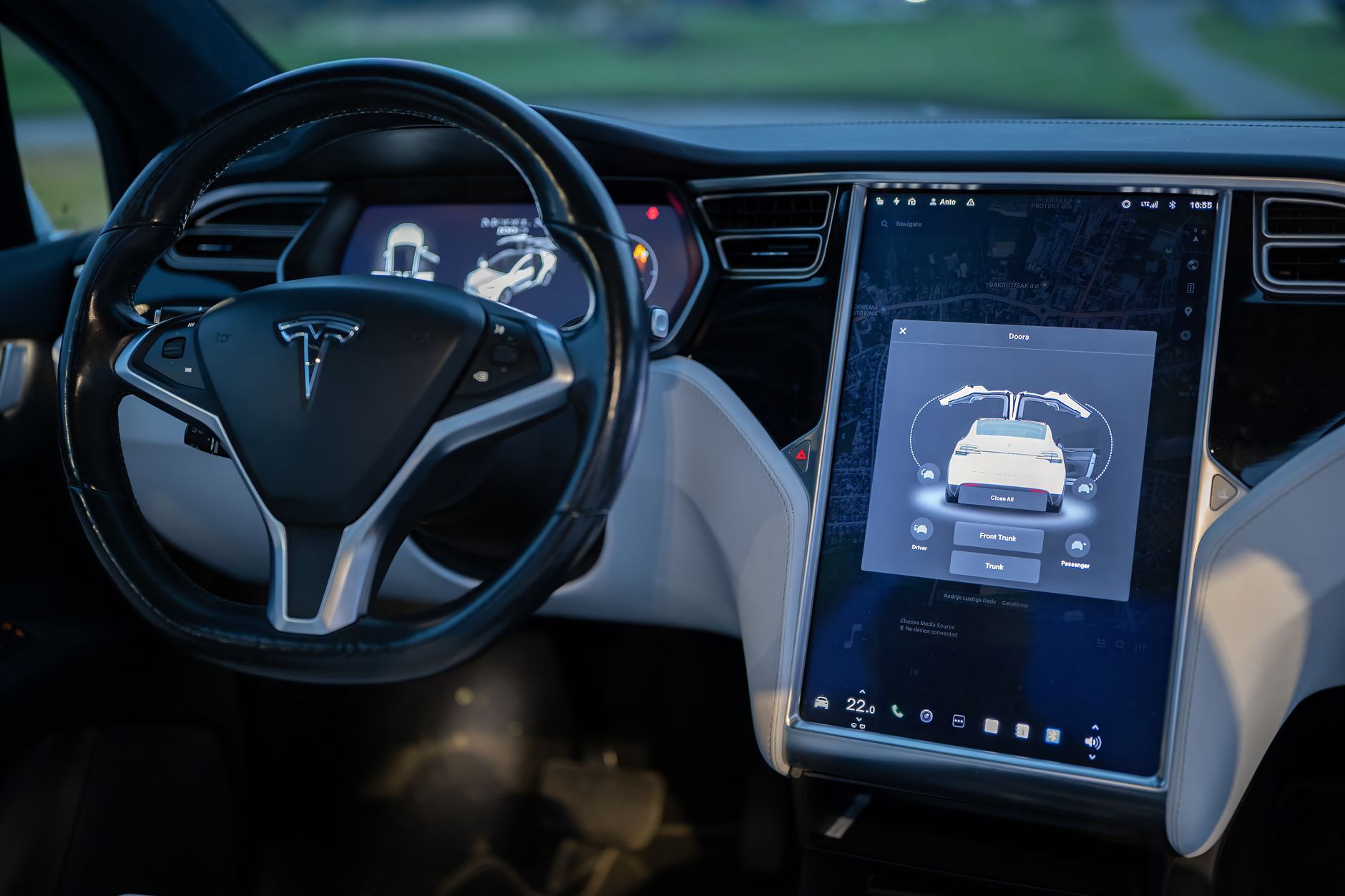 a sleek, doorhandle-free autonomous electric vehicle parked at a curbside pickup zone on an urban street, with no steering wheel visible through the windshield