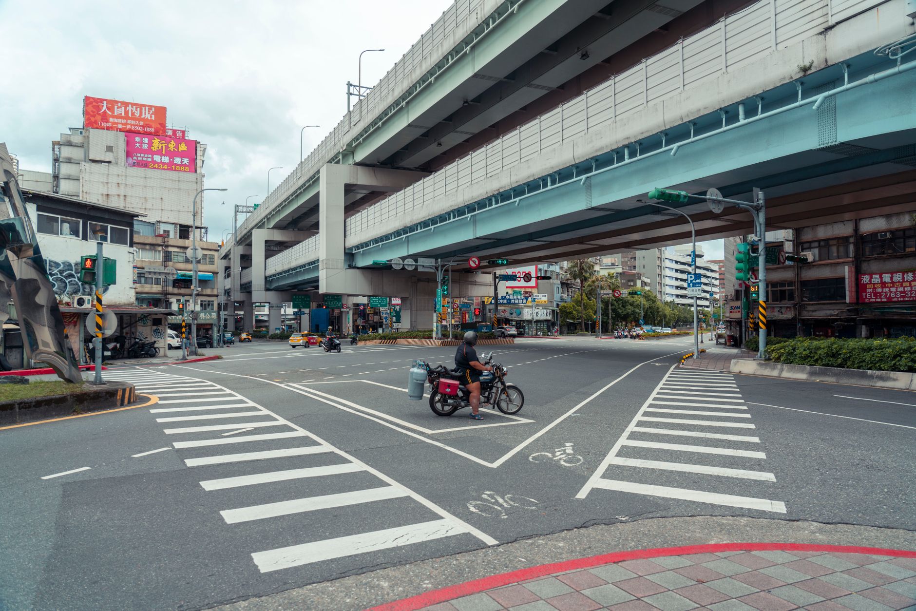 a wide shot of an empty urban intersection at dusk with traffic signals and lane markings, illustrating the kind of complex environment an autonomous vehicle must navigate without human input