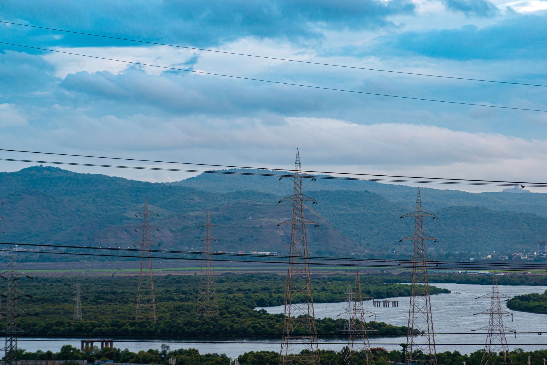 aerial view of a large hyperscale data center campus surrounded by power substations and transmission lines in a flat rural landscape