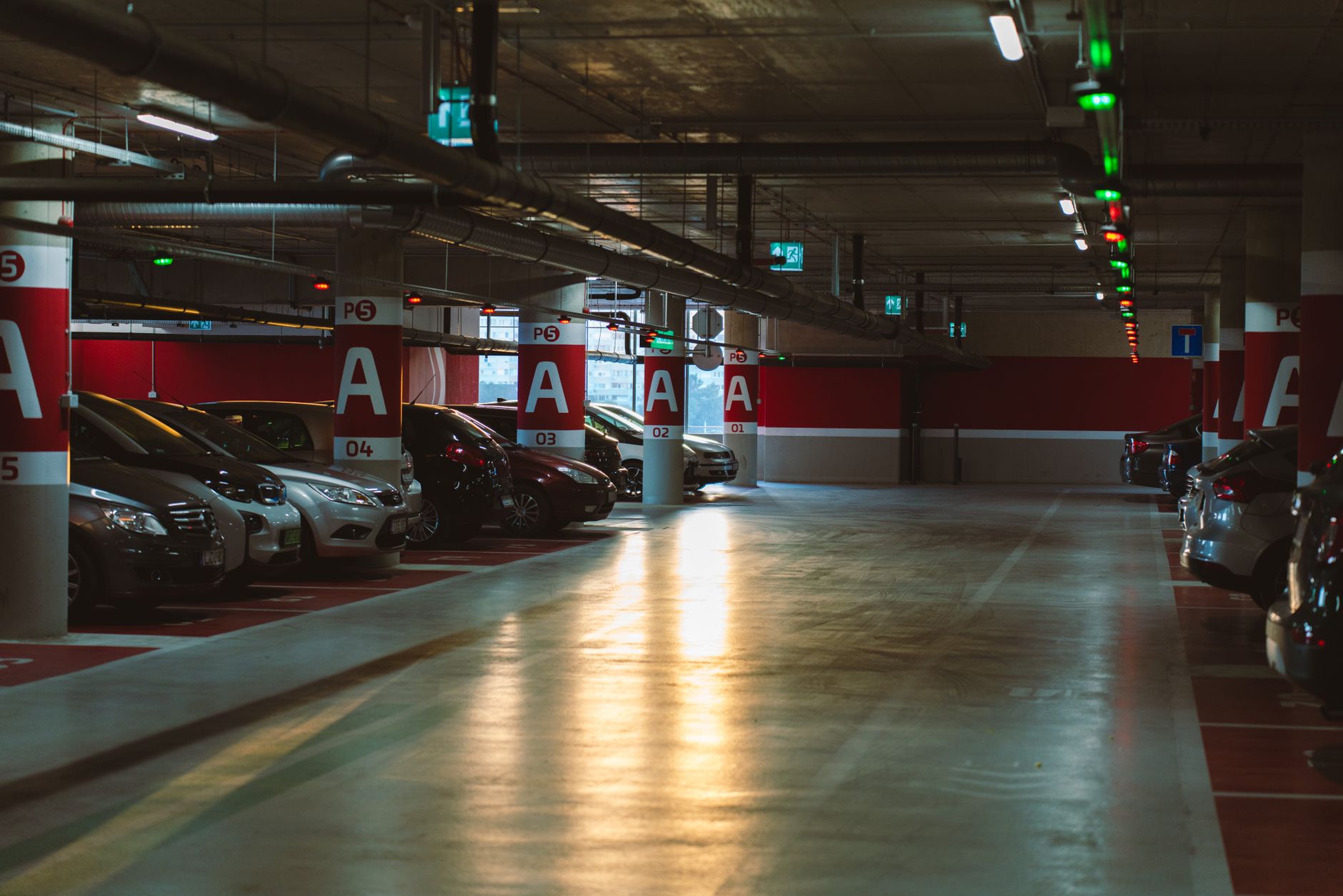 a row of white autonomous vehicle sensor pods mounted on car rooftops in an open urban parking facility, late afternoon light casting long shadows