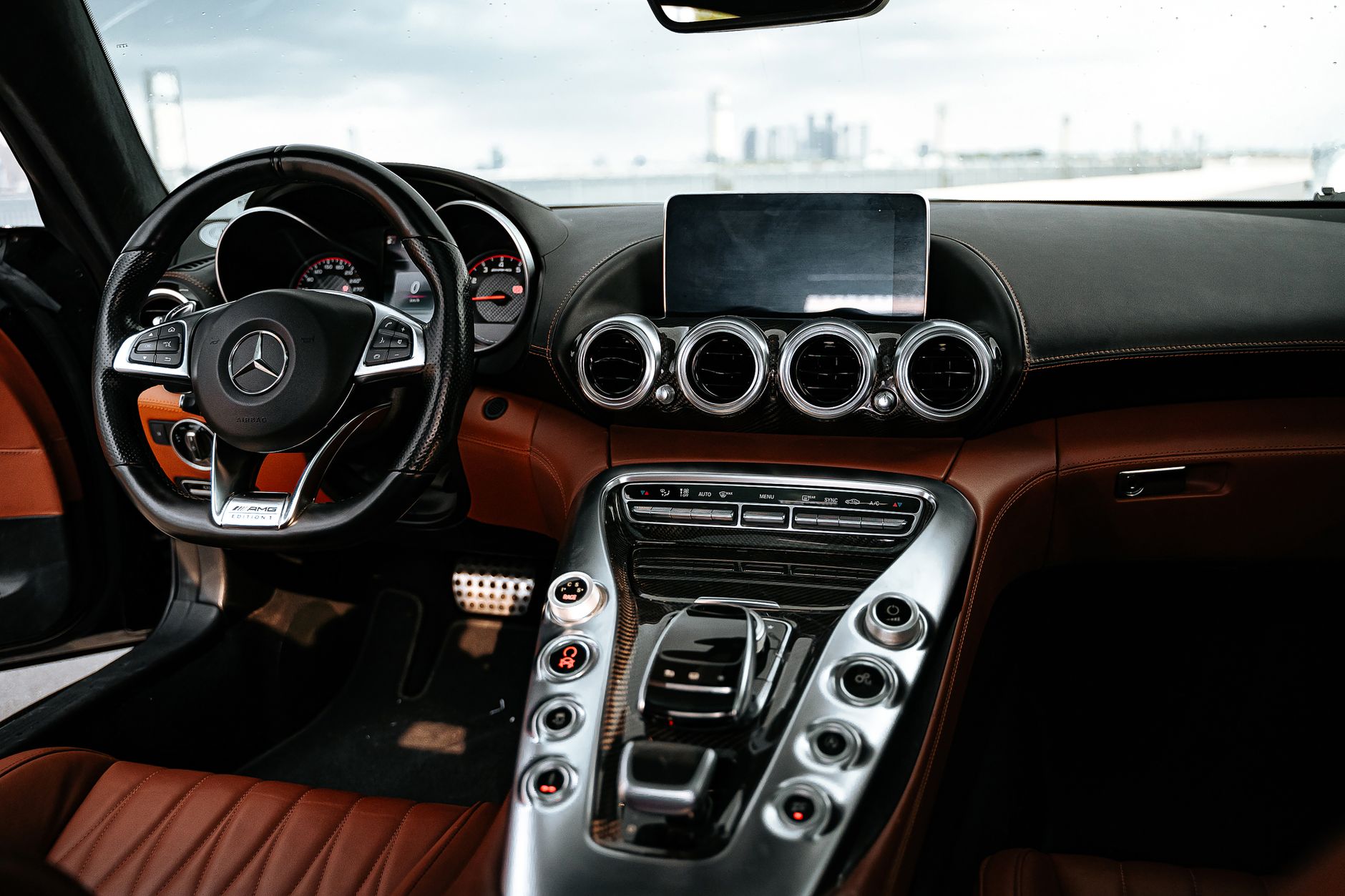 the interior of an empty autonomous vehicle cabin showing a center console screen, side-mounted cameras, and ambient cabin lighting with no steering wheel present