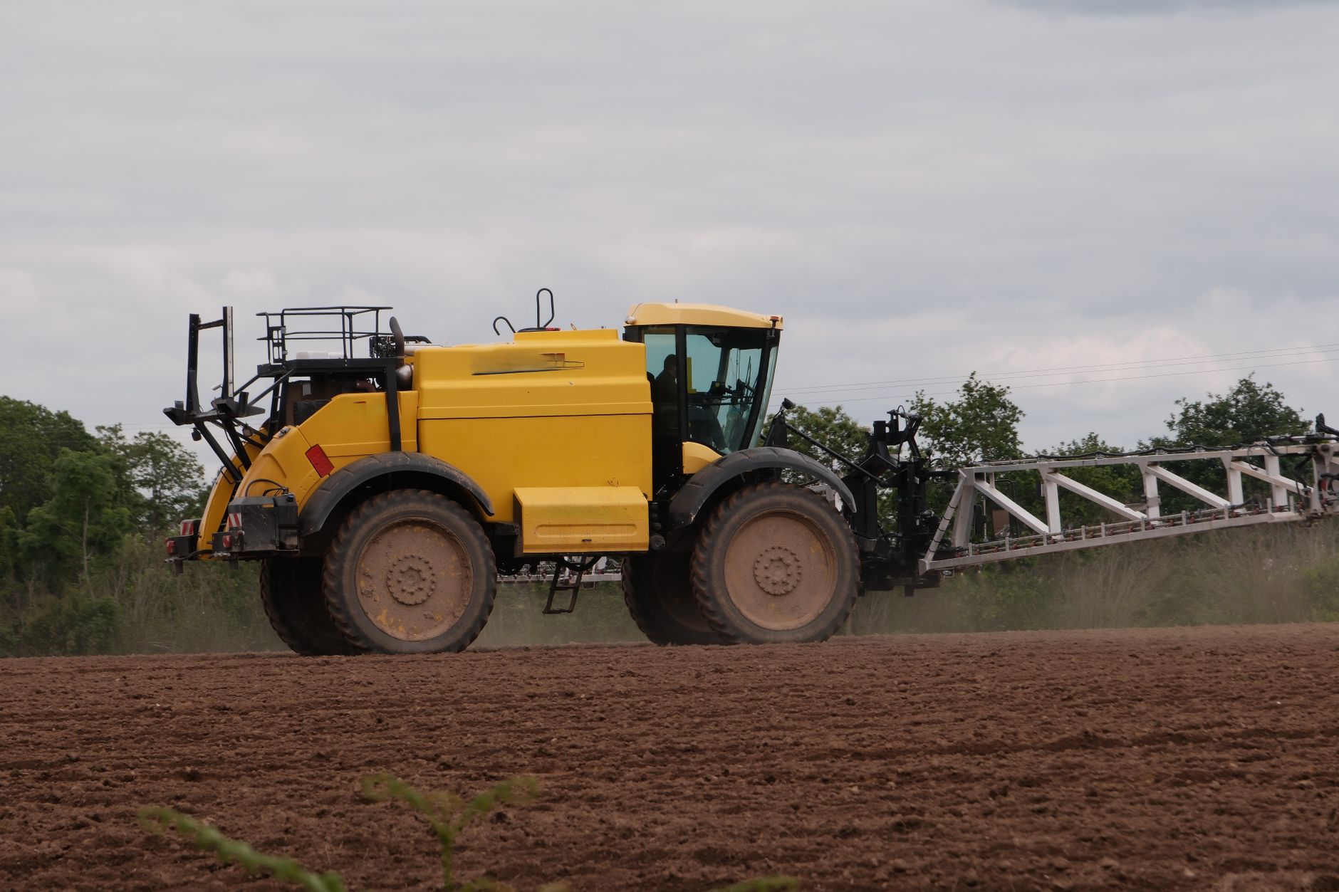 A large autonomous tractor moving through an open crop field at golden hour, with GPS antenna arrays visible on the cab roof and rows of freshly tilled soil stretching to the horizon