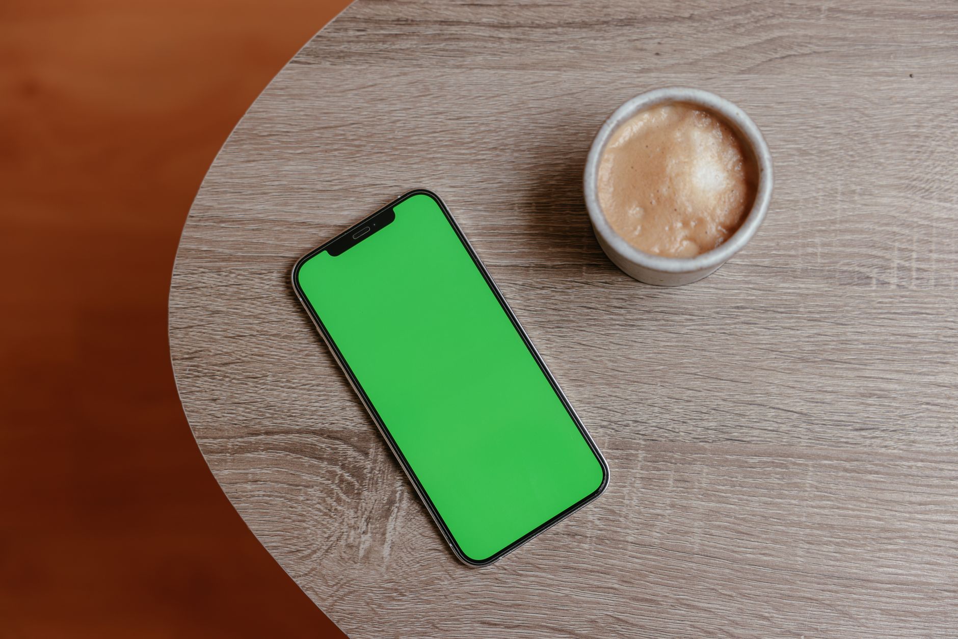 a smartphone screen displaying an active SMS conversation thread with short automated response bubbles, resting on a wooden desk beside a coffee cup