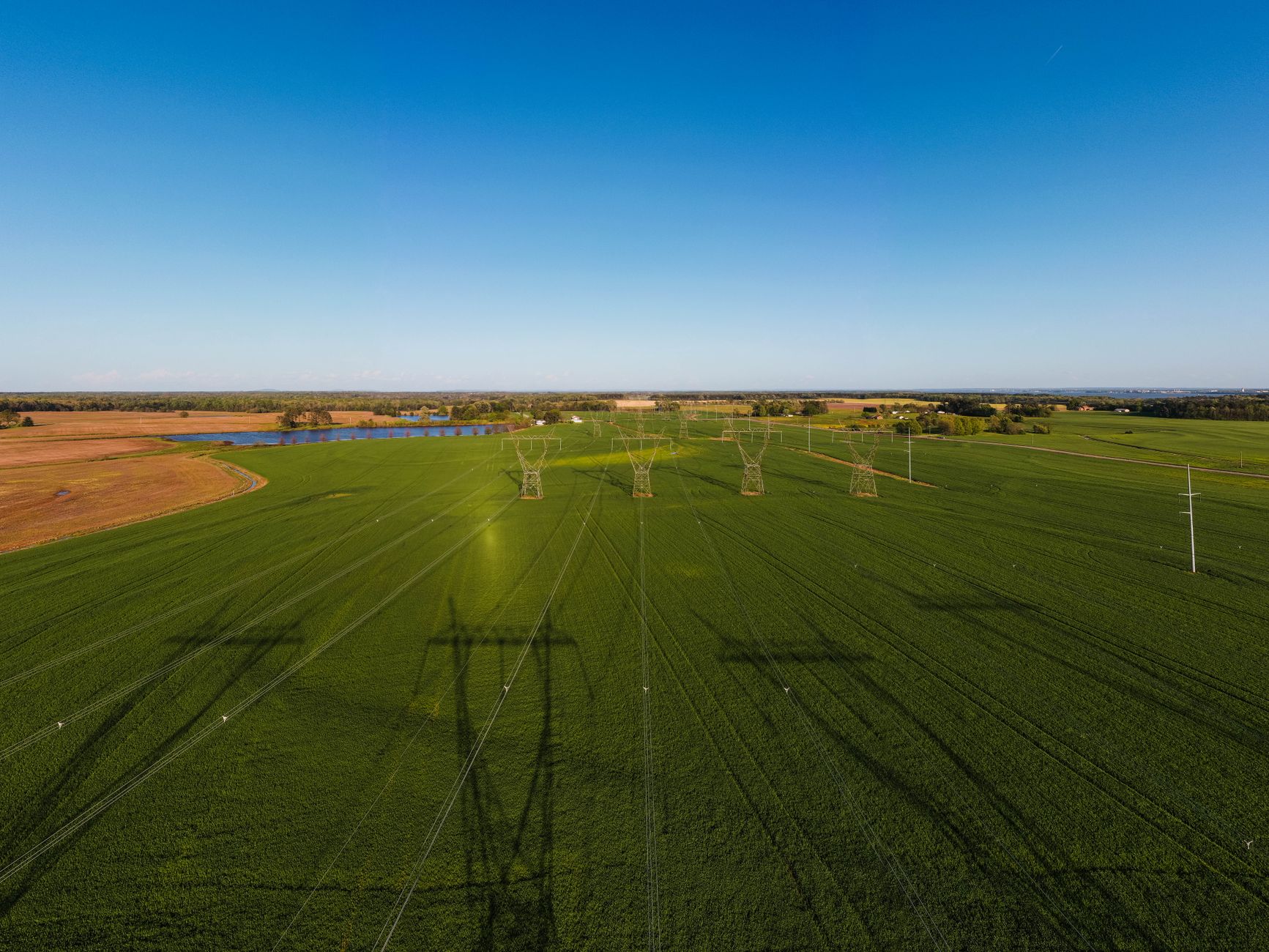 wide aerial view of a large hyperscale data center campus surrounded by rural land, electrical substations visible along the perimeter