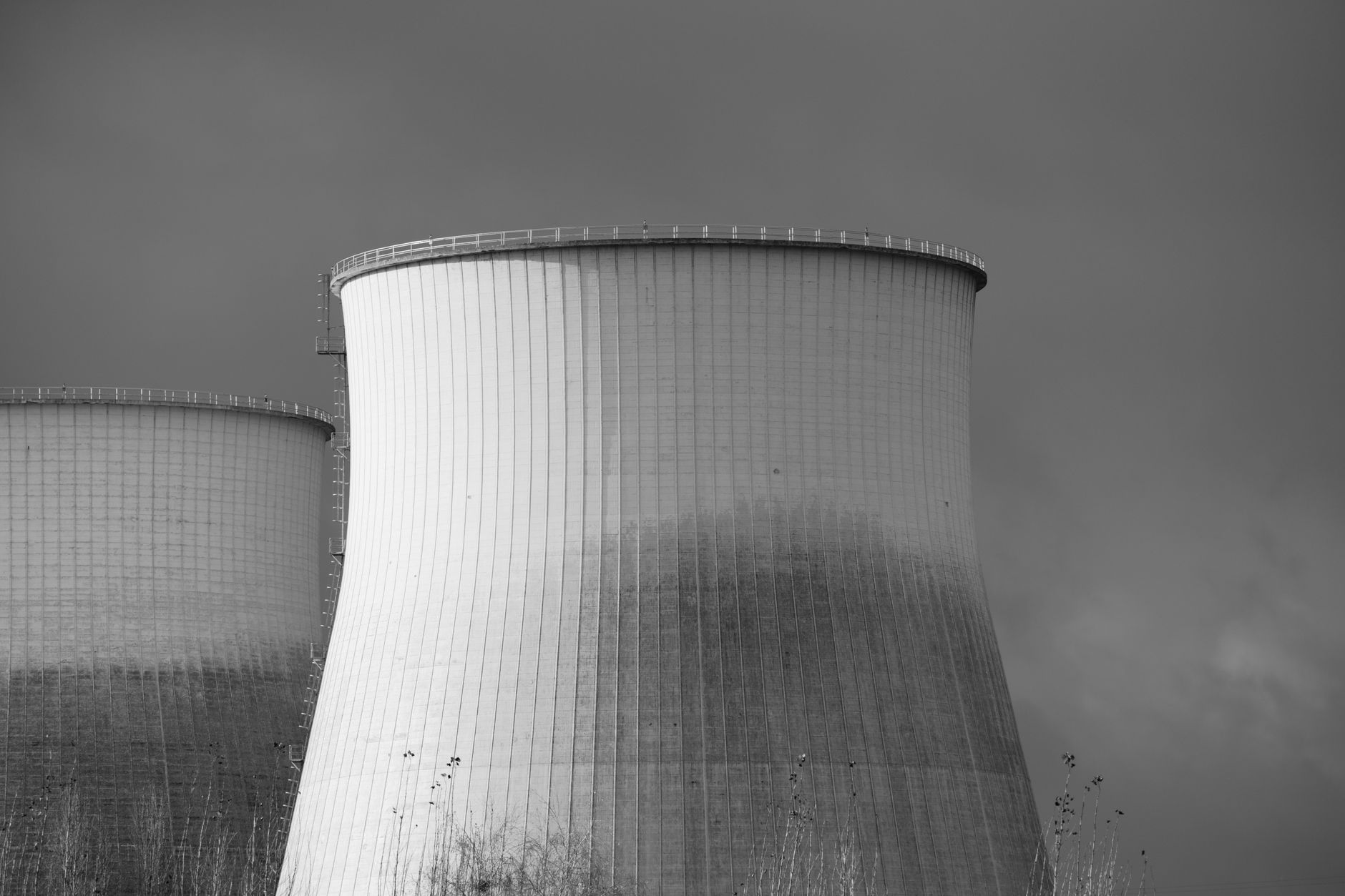 rows of cooling towers and electrical transformers outside a large data center facility on a cloudy afternoon, no people visible