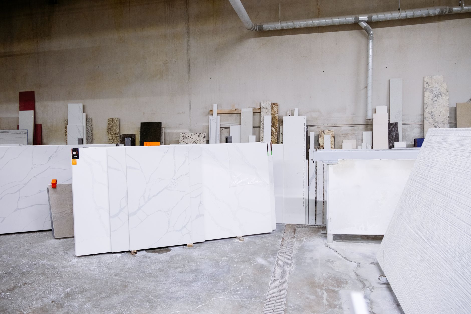 a fabrication workshop interior with industrial stone cutting equipment and thick dust particles visible in the air near a slab-cutting machine
