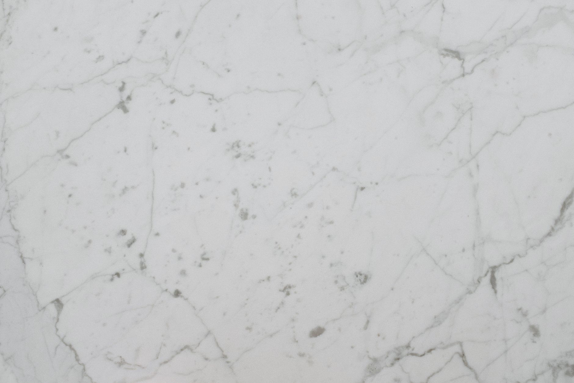 close-up of a large engineered stone countertop slab resting on a fabrication shop floor, showing its dense, uniform surface texture under industrial lighting