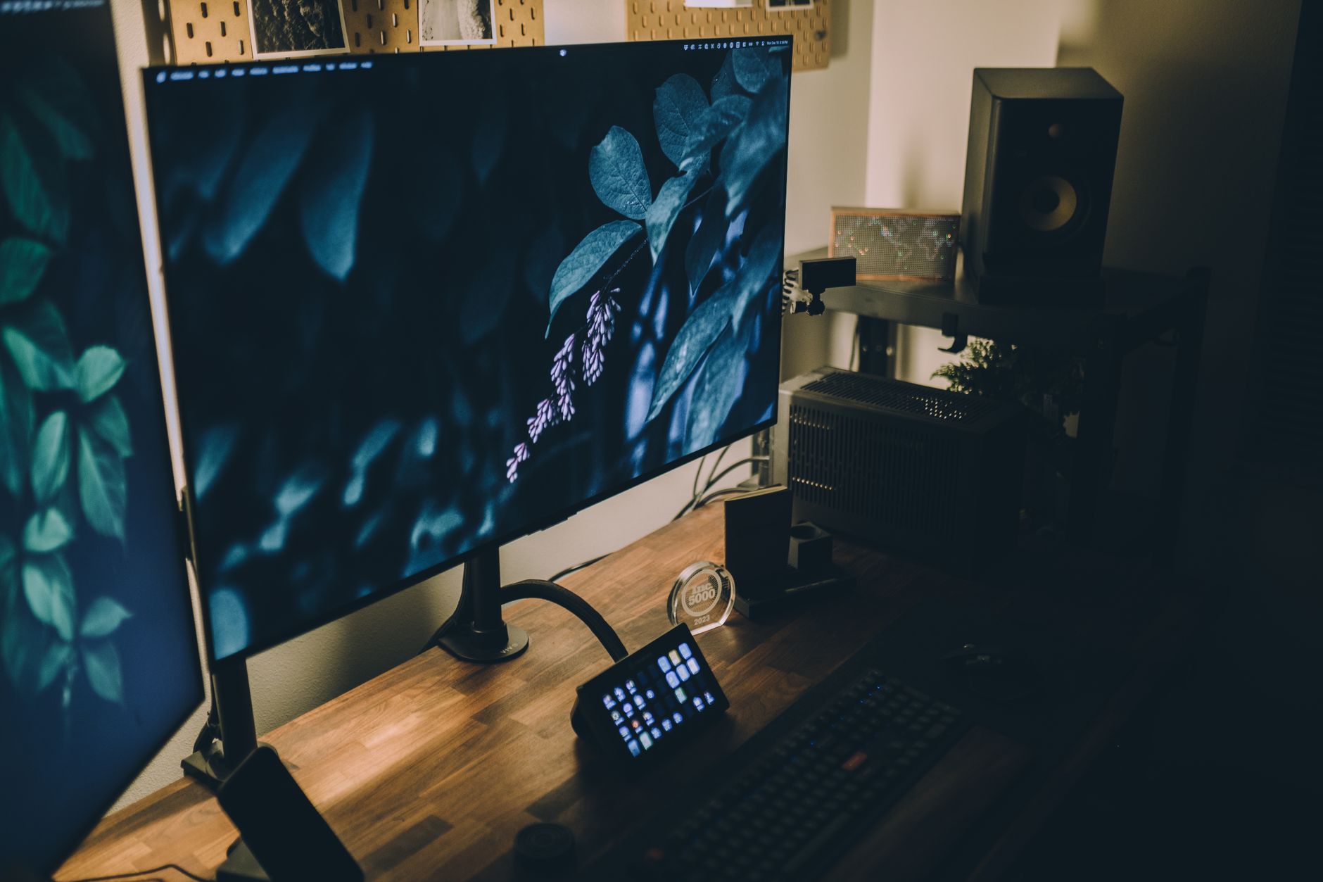 a terminal screen displaying Kubernetes cluster node status output in a darkened office environment, keyboard and monitor in frame