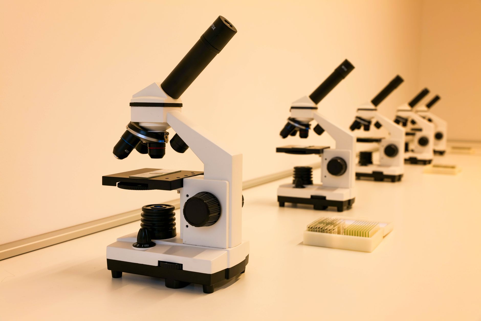 optical bench setup with laser source aimed at a suspended thin-film sample, surrounded by photodetectors and spectrometer fiber optics