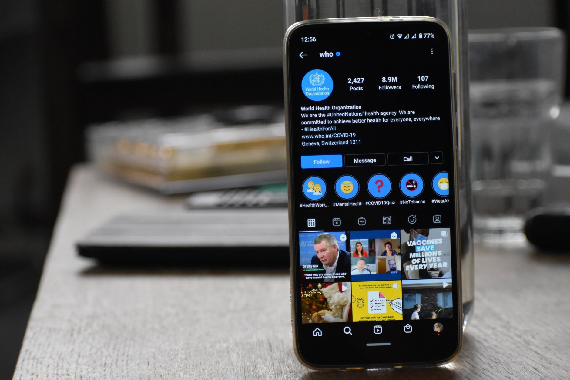 a smartphone displaying a social media feed on a wooden desk next to a closed school textbook, soft natural window light