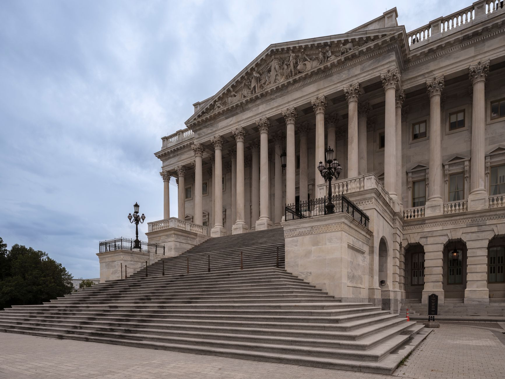 exterior view of a federal courthouse entrance with stone columns and concrete steps, overcast sky