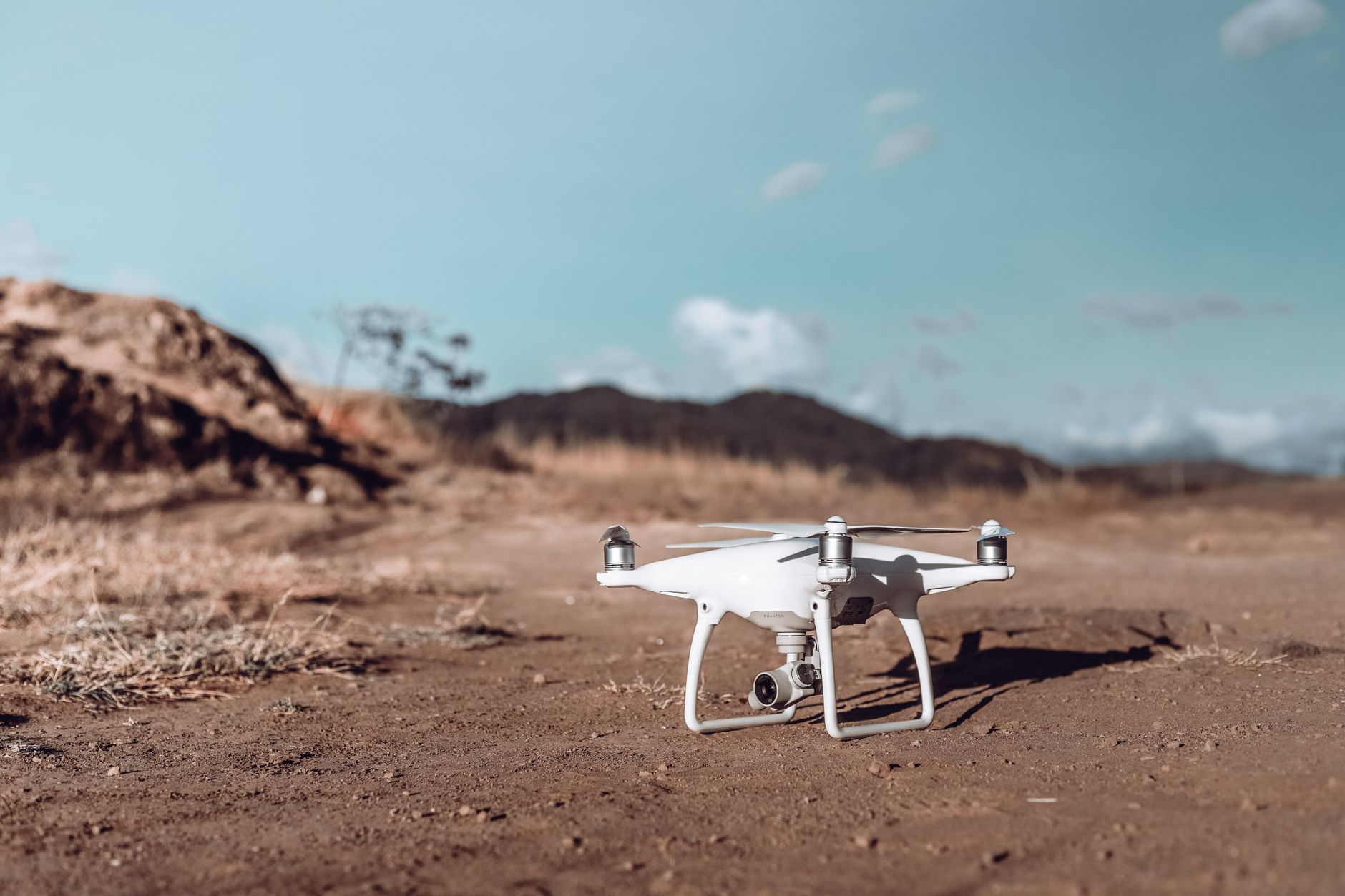an unmanned ground vehicle on a dusty military testing range with sensor arrays mounted on its frame, photographed from a low wide angle at dusk