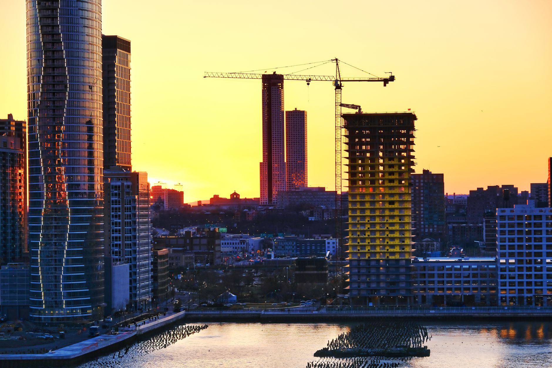 aerial view of a modern tech campus in Tel Aviv at golden hour, glass office buildings reflecting the skyline with construction cranes visible in the background