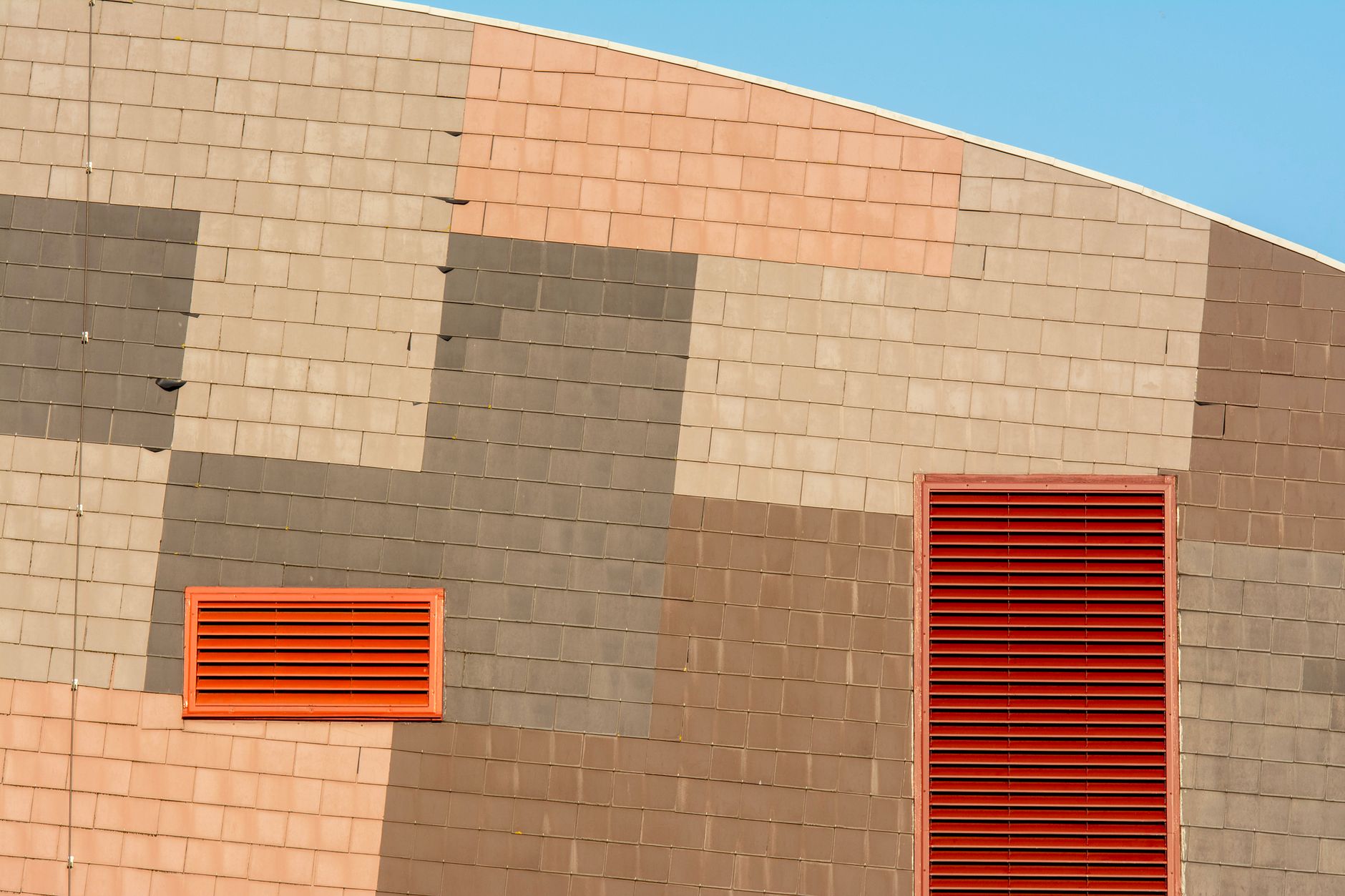 a wide-angle shot of a modern data center exterior at dusk, with cooling units humming along the building's facade and warm light visible through ventilation grates