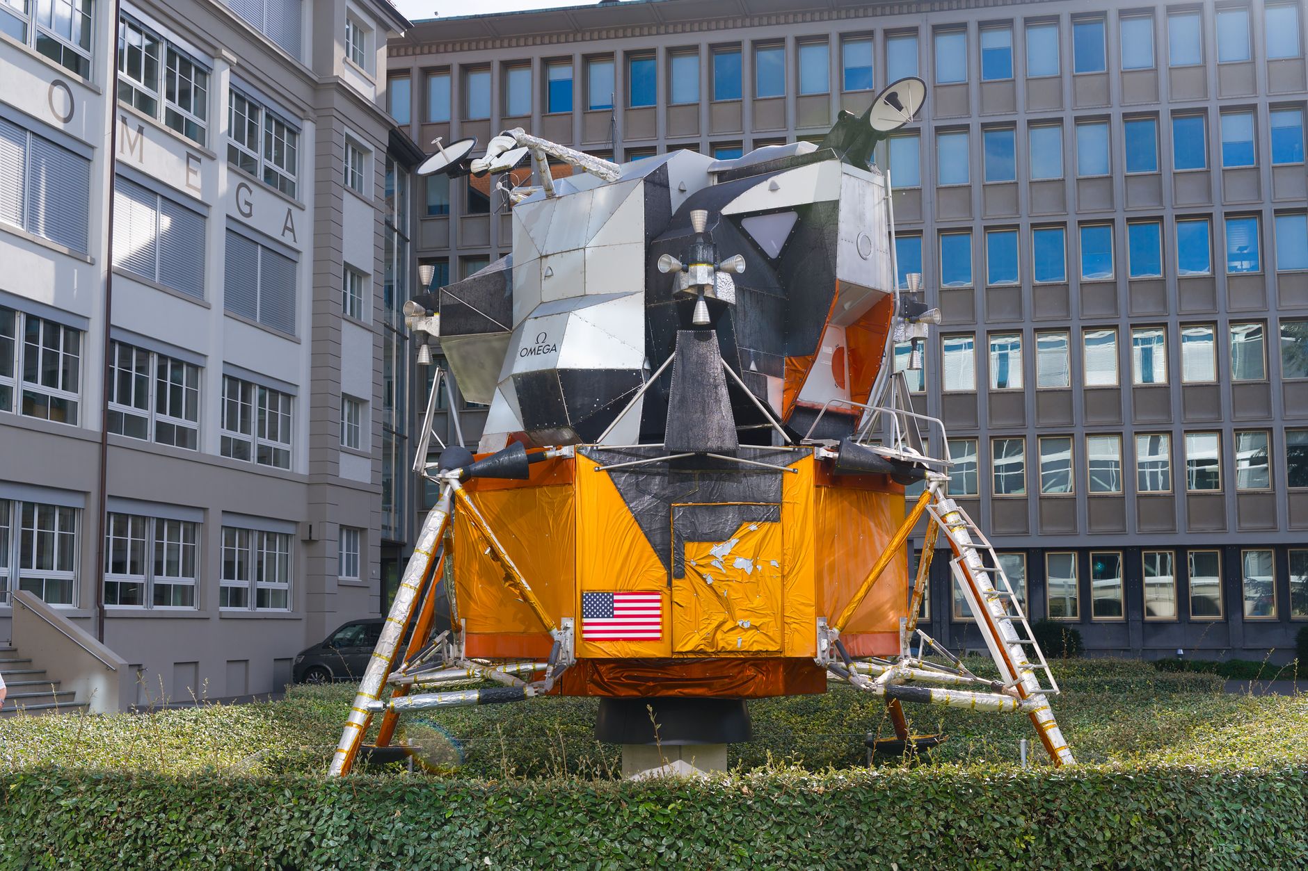 a close-up of a scaled replica of the Apollo lunar module spacecraft model on a display stand, with mission patches and technical schematics visible in the background
