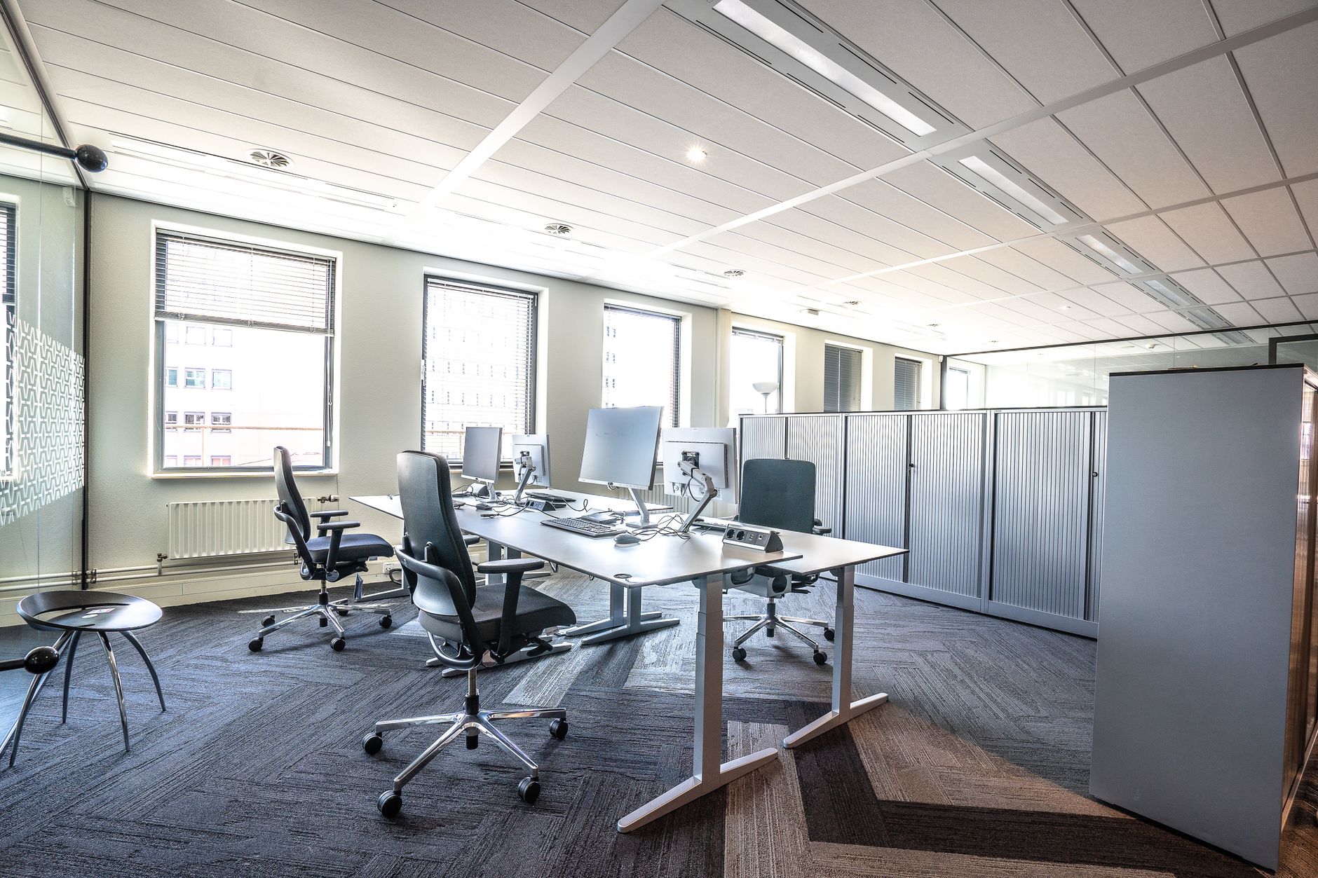 rows of sleek workstations inside a bright, open-plan technology office with large windows overlooking an urban skyline