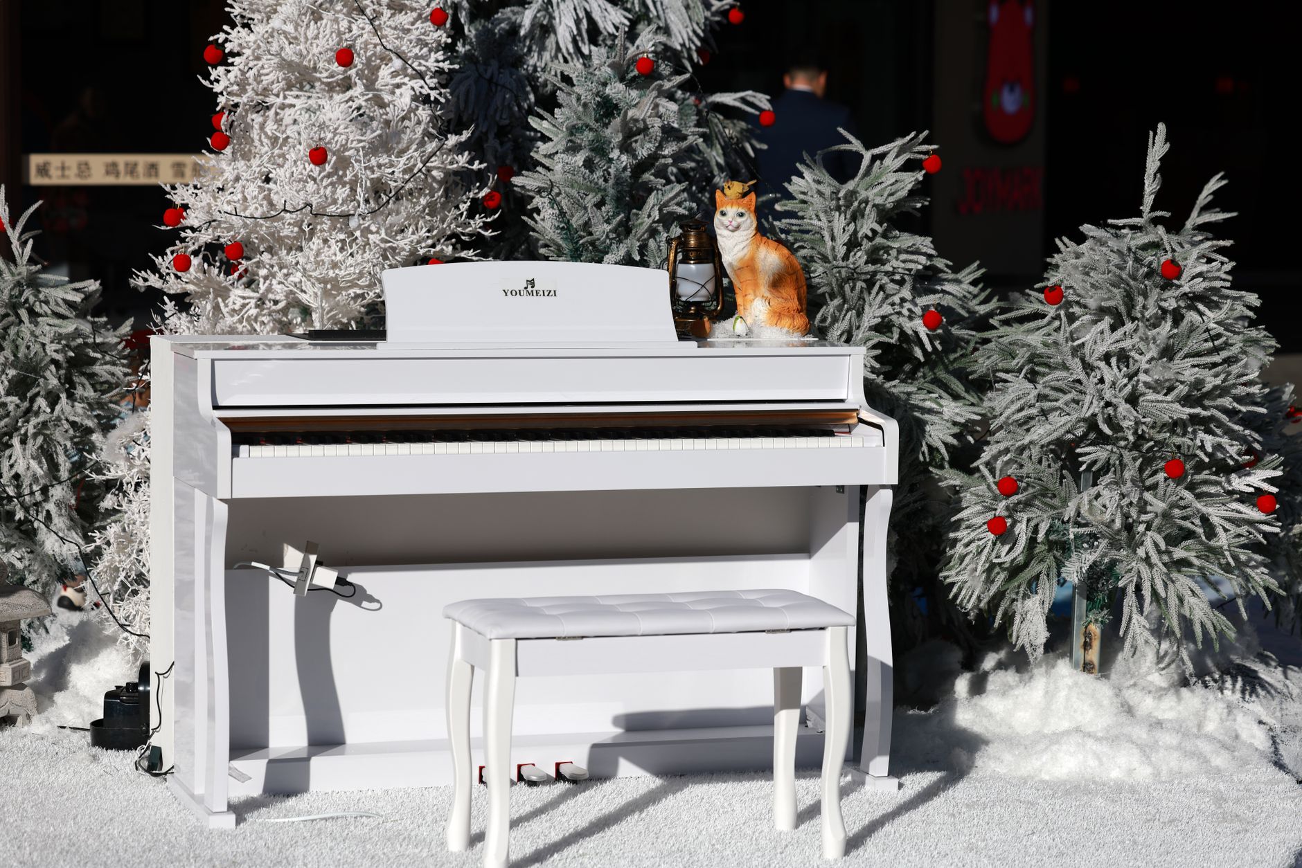 a small pre-lit artificial Christmas tree on a wooden desk beside a window with snow visible outside