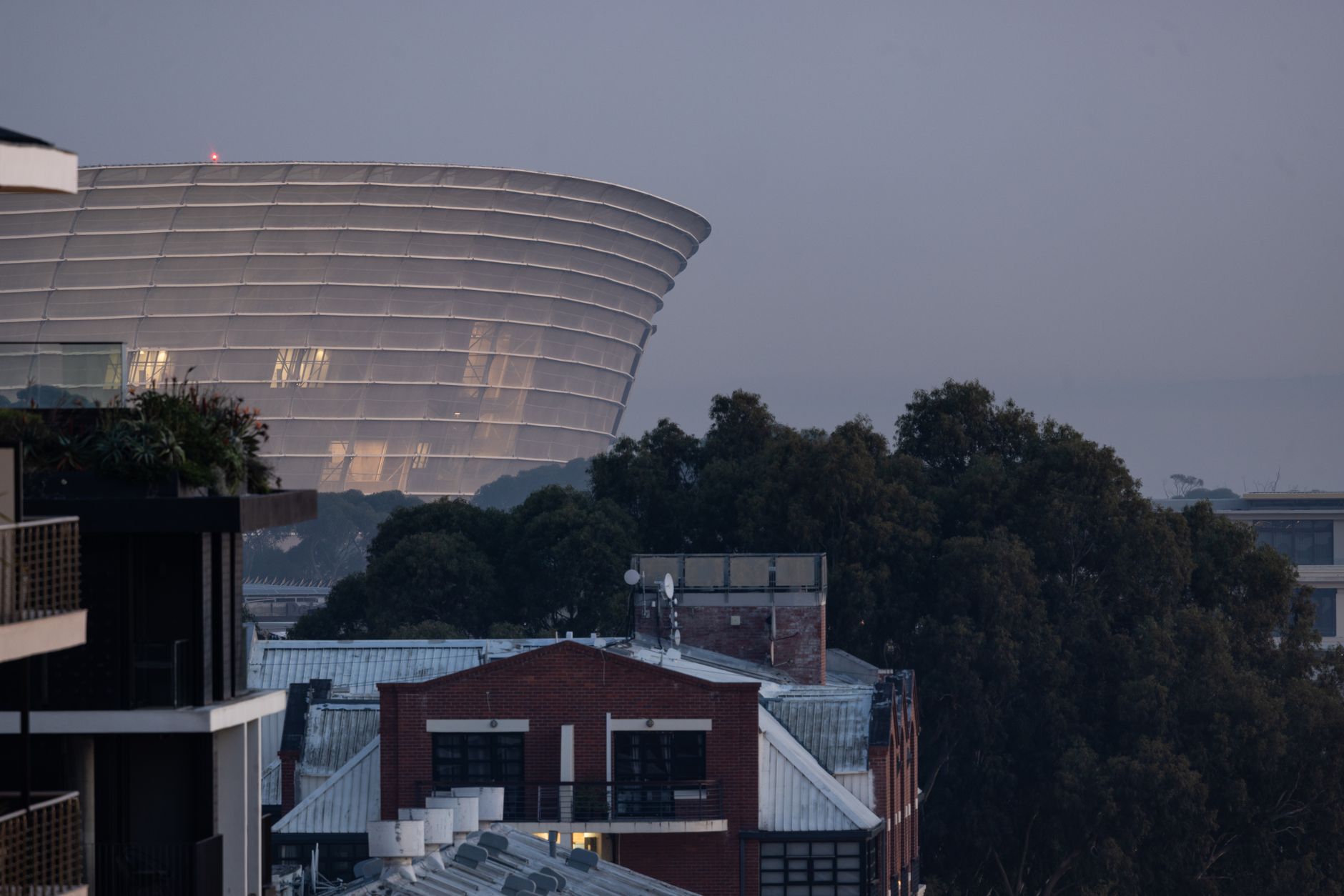 a wide-angle view of a modern cloud data center exterior at dusk, satellite dishes and cooling units visible along the roofline