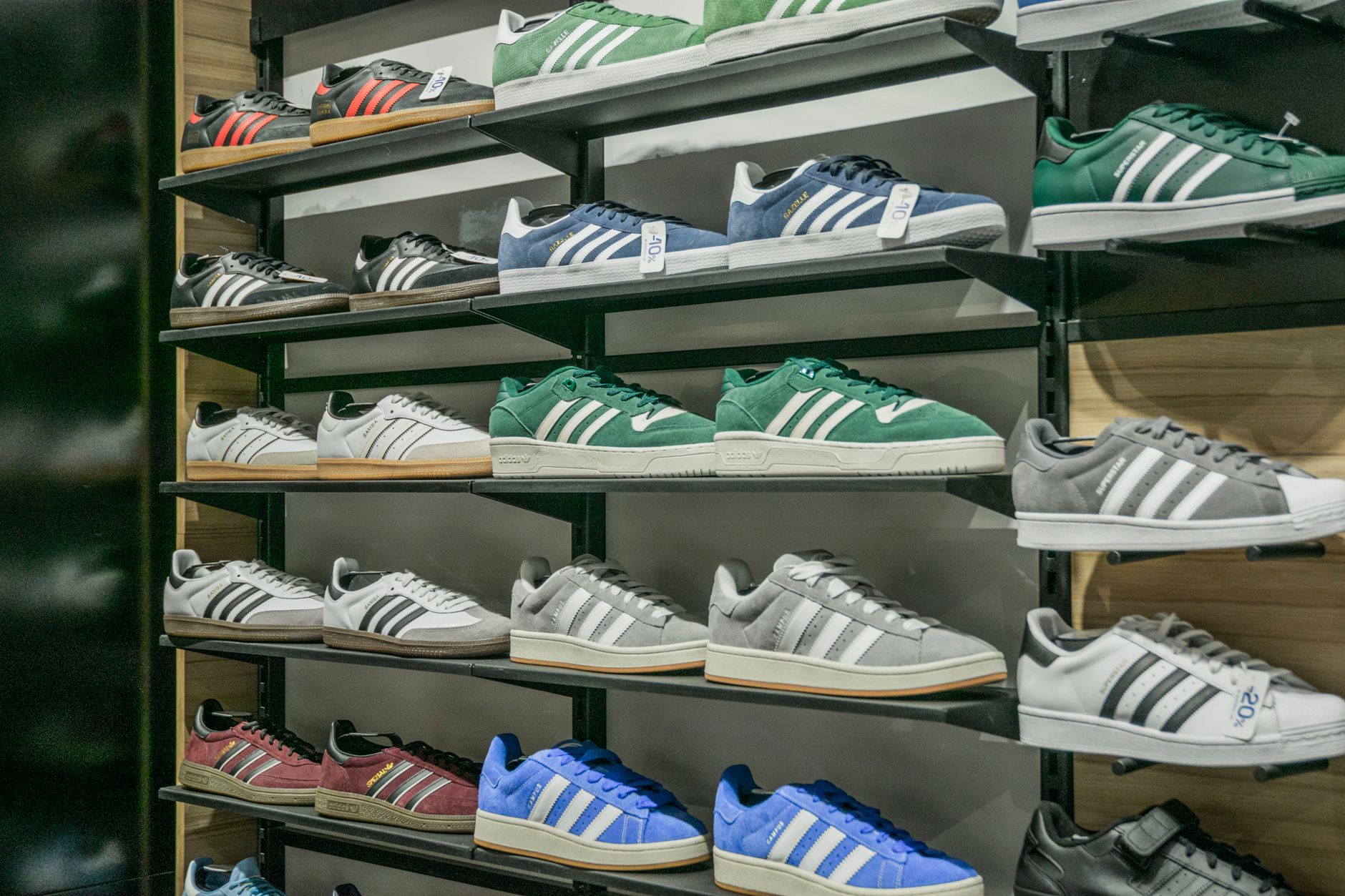 rows of branded sneakers displayed on a retail shelf under warm store lighting, with no visible text or signage
