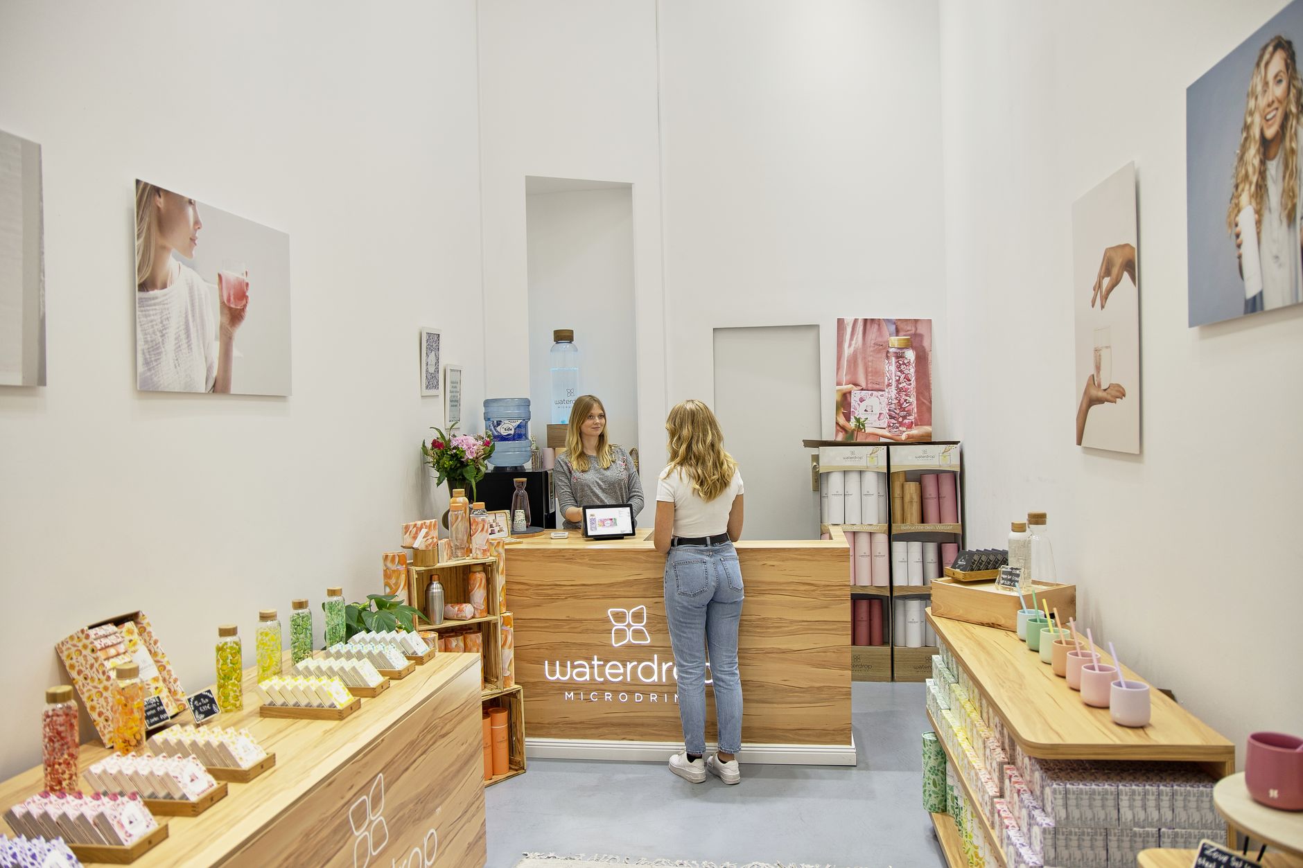 a tablet propped on a retail counter displaying a TikTok Shop storefront interface with product listings and a checkout panel, inside a small warehouse with shelving in the background
