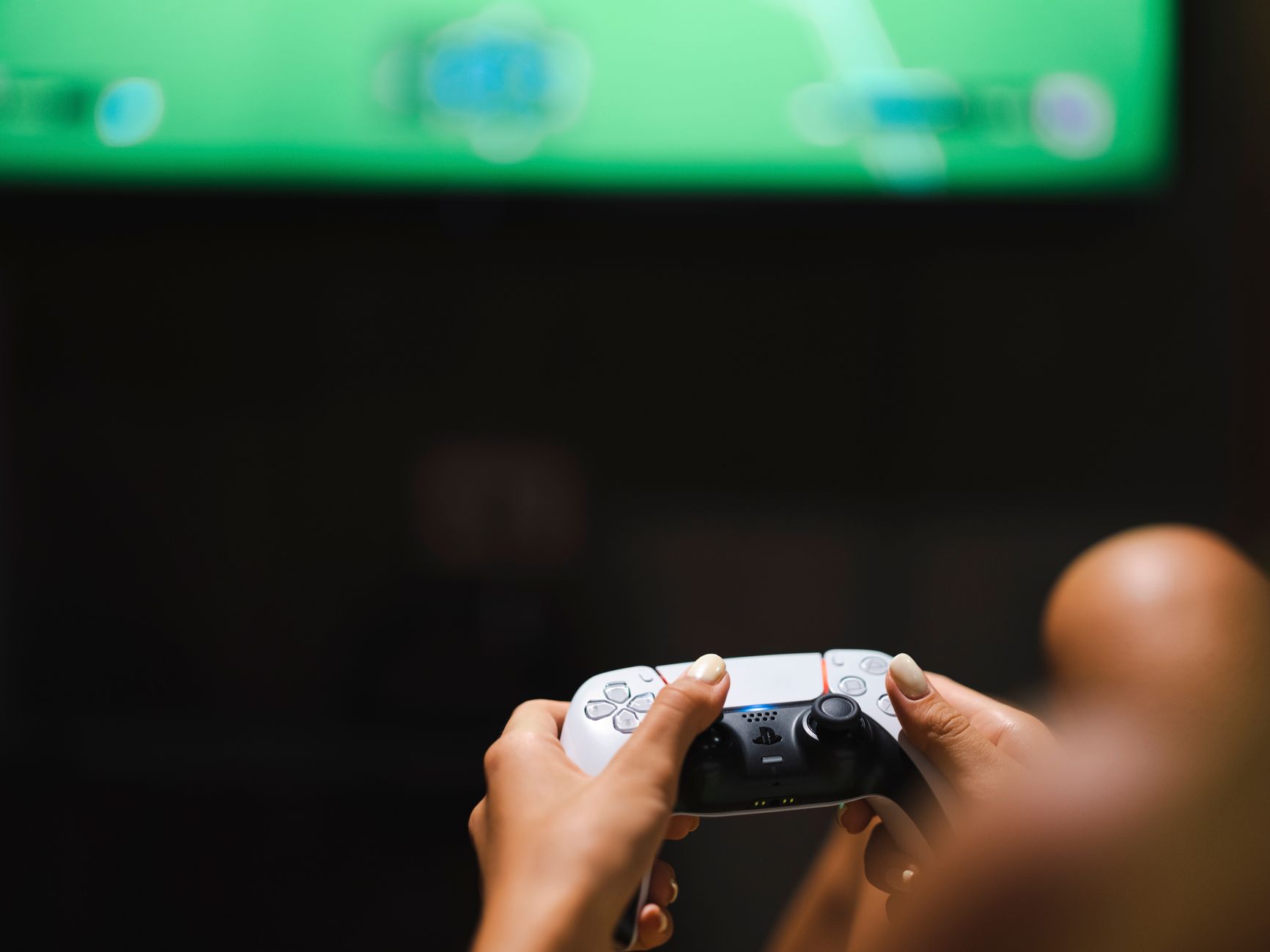 a large flat-screen television mounted in a modern living room displaying a cloud gaming interface, with a wireless game controller resting on a coffee table in the foreground